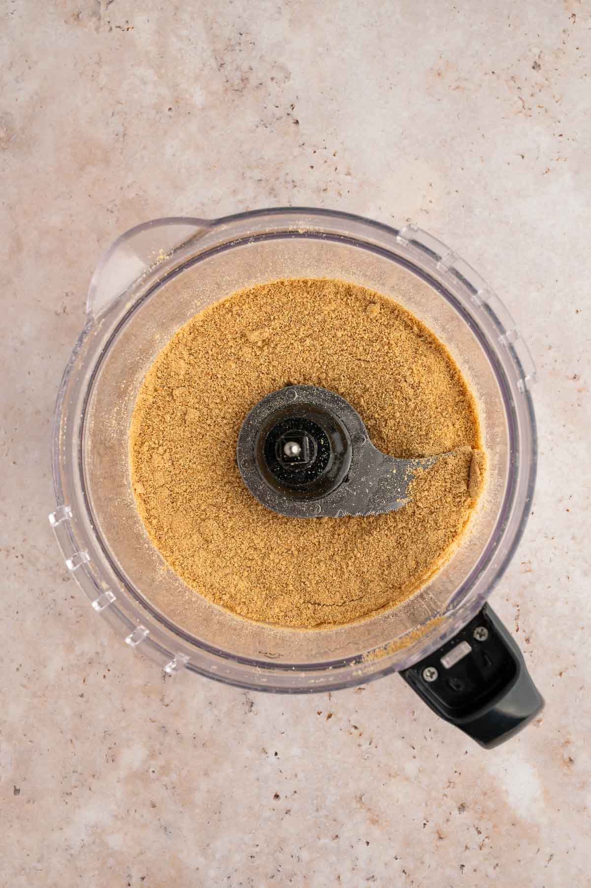 Graham crackers in a food processor after being ground into fine crumbs.