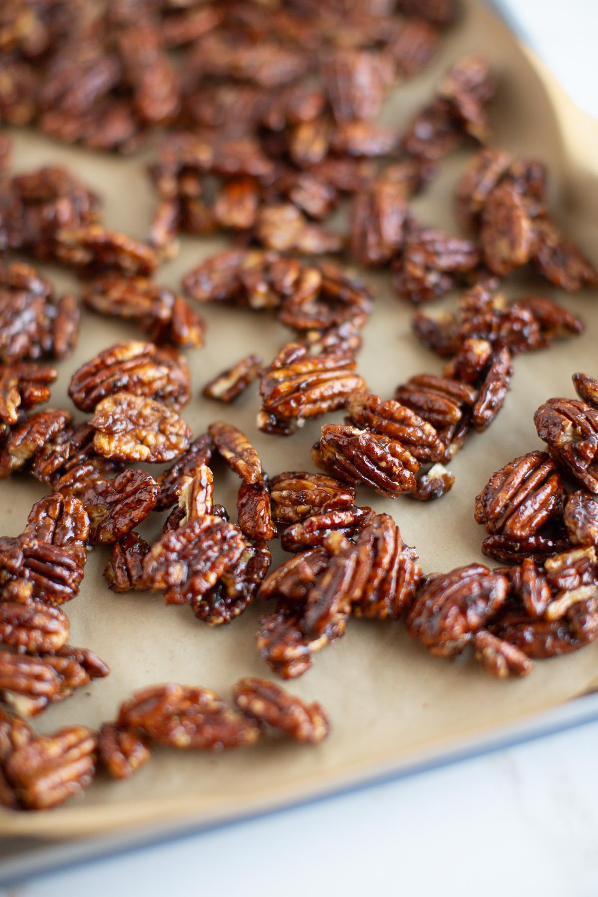 A parchment-lined baking tray with candied pecans.