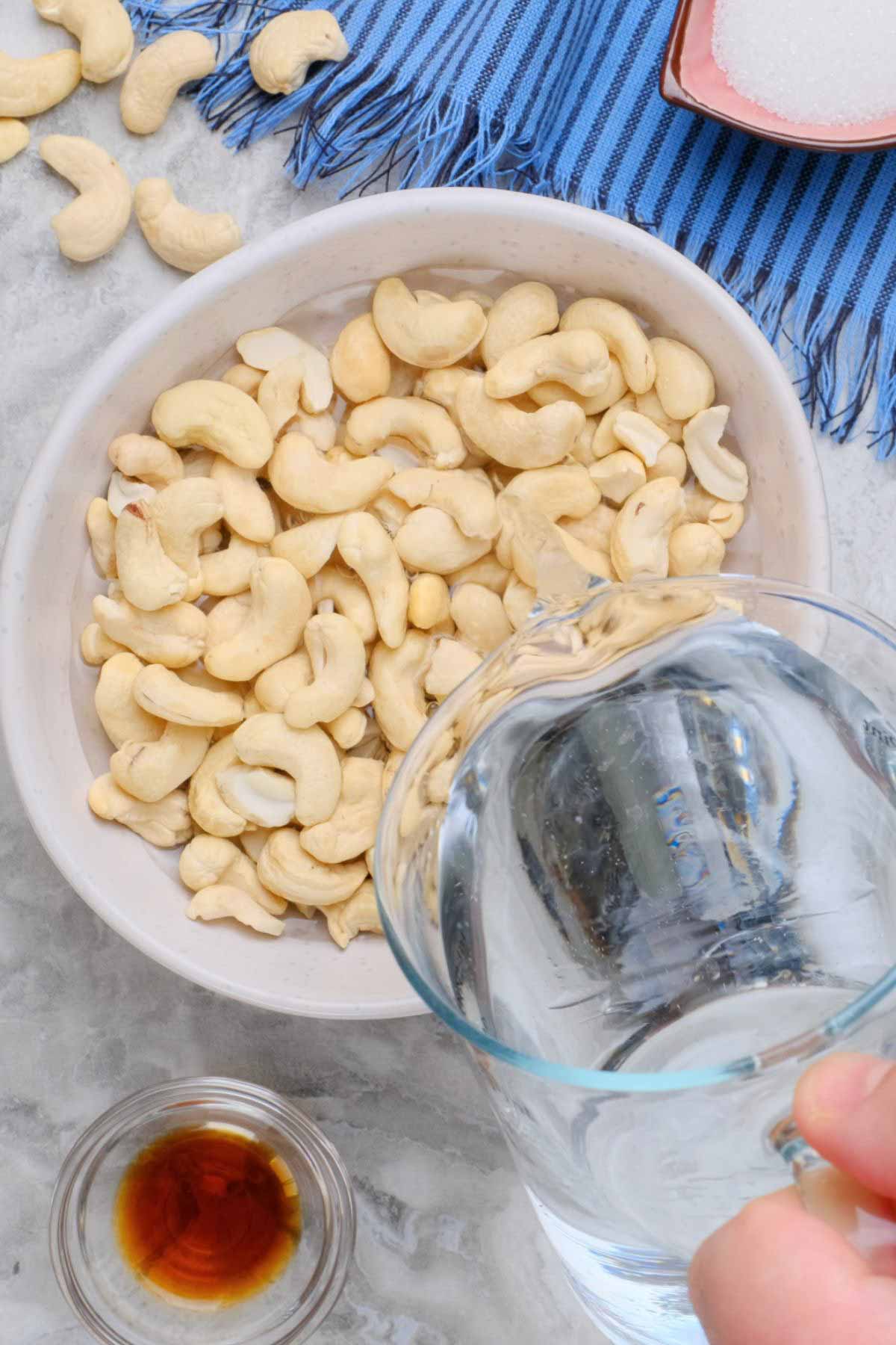 Water being poured into a bowl of cashews.