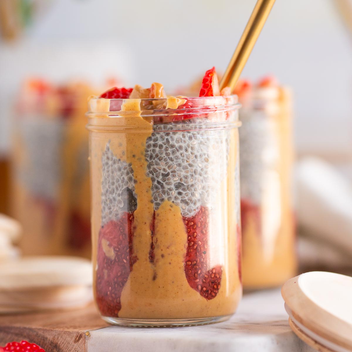 Peanut butter and jelly chia pudding parfait layered in a jar with strawberry jam compote, vanilla chia pudding, and peanut butter.