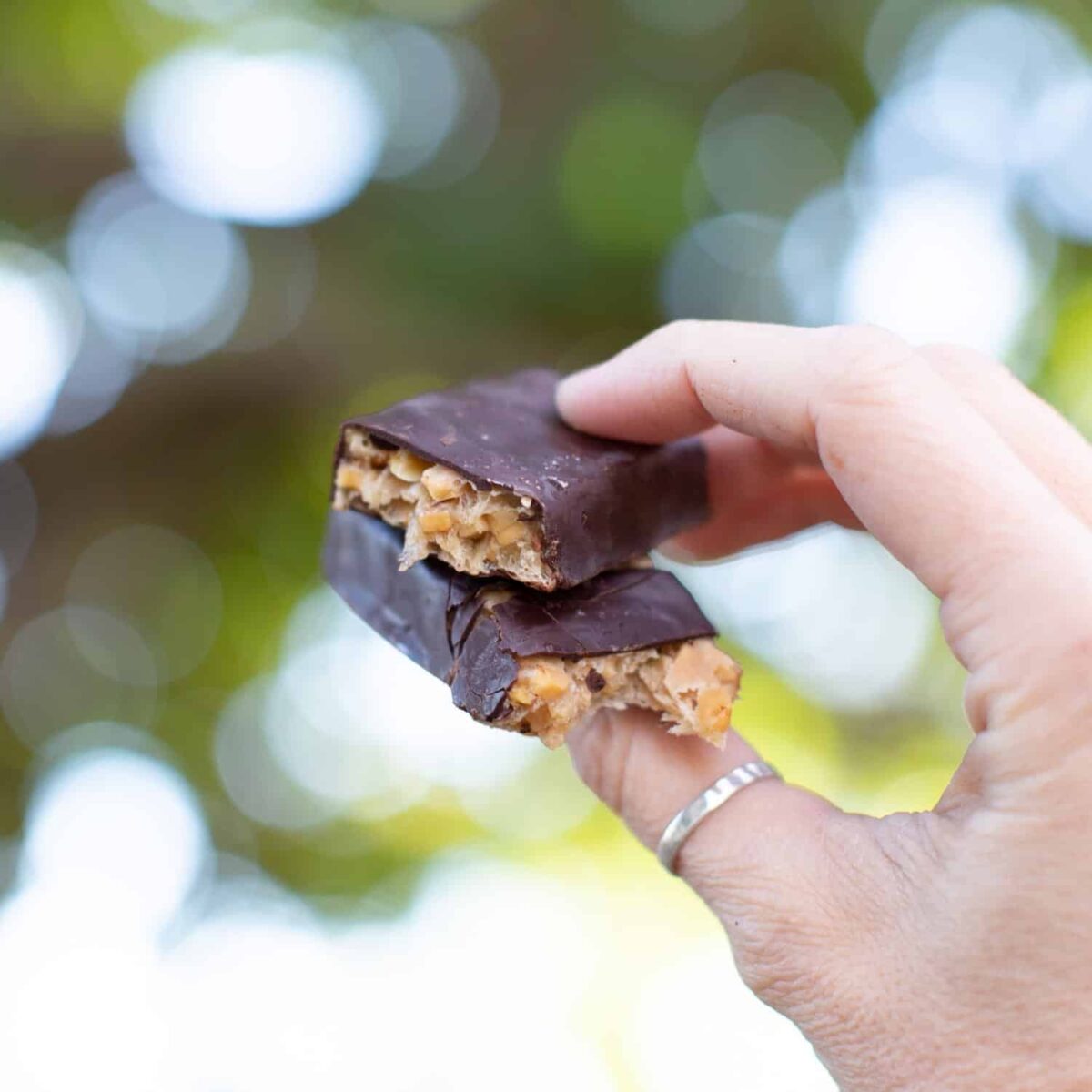 A hand holding homemade vegan snickers bars.