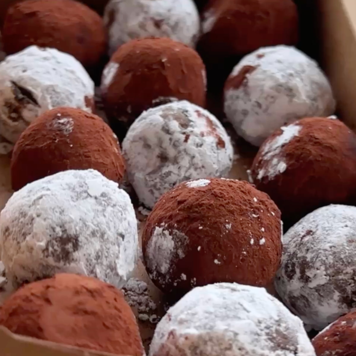A box of chocolate brain ball truffles with half dipped in cocoa powder and half dipped in powdered sugar.