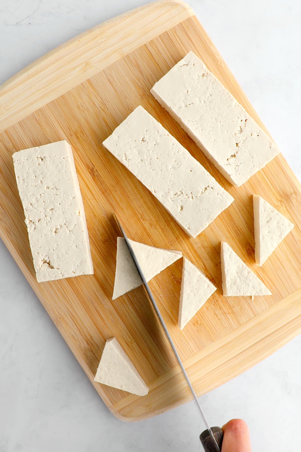 Tofu sliced into triangles on a cutting board.