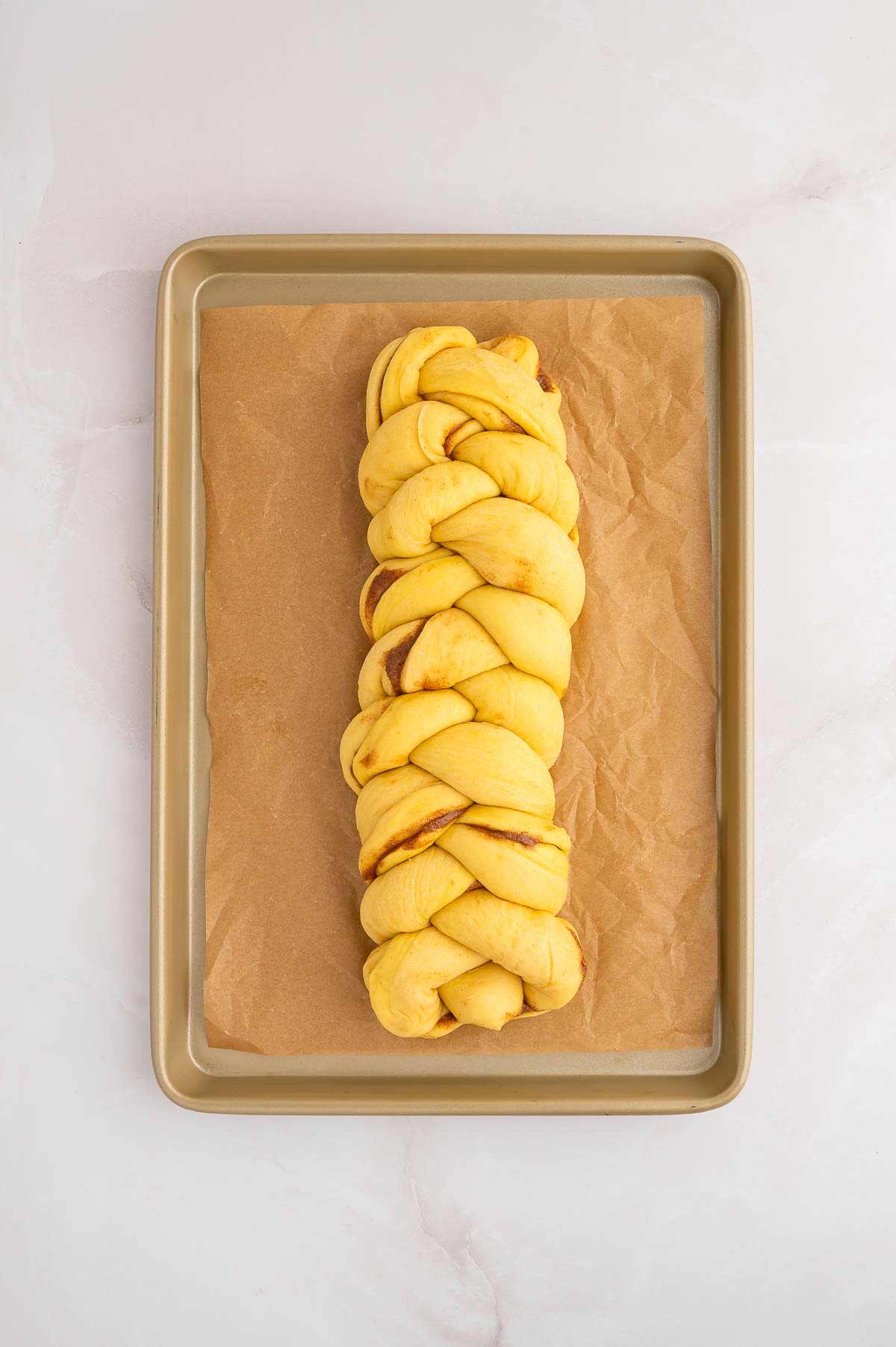 A braided loaf of vegan cinnamon challah on a baking sheet.