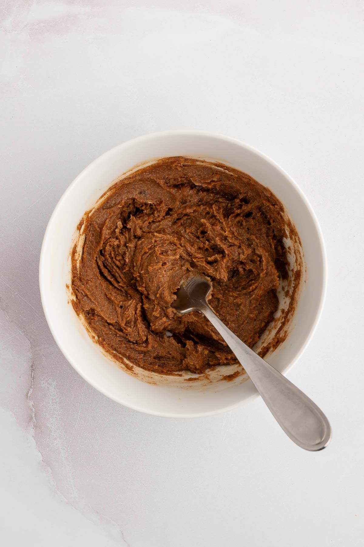 A bowl of sweet filling for cinnamon challah with a spoon.