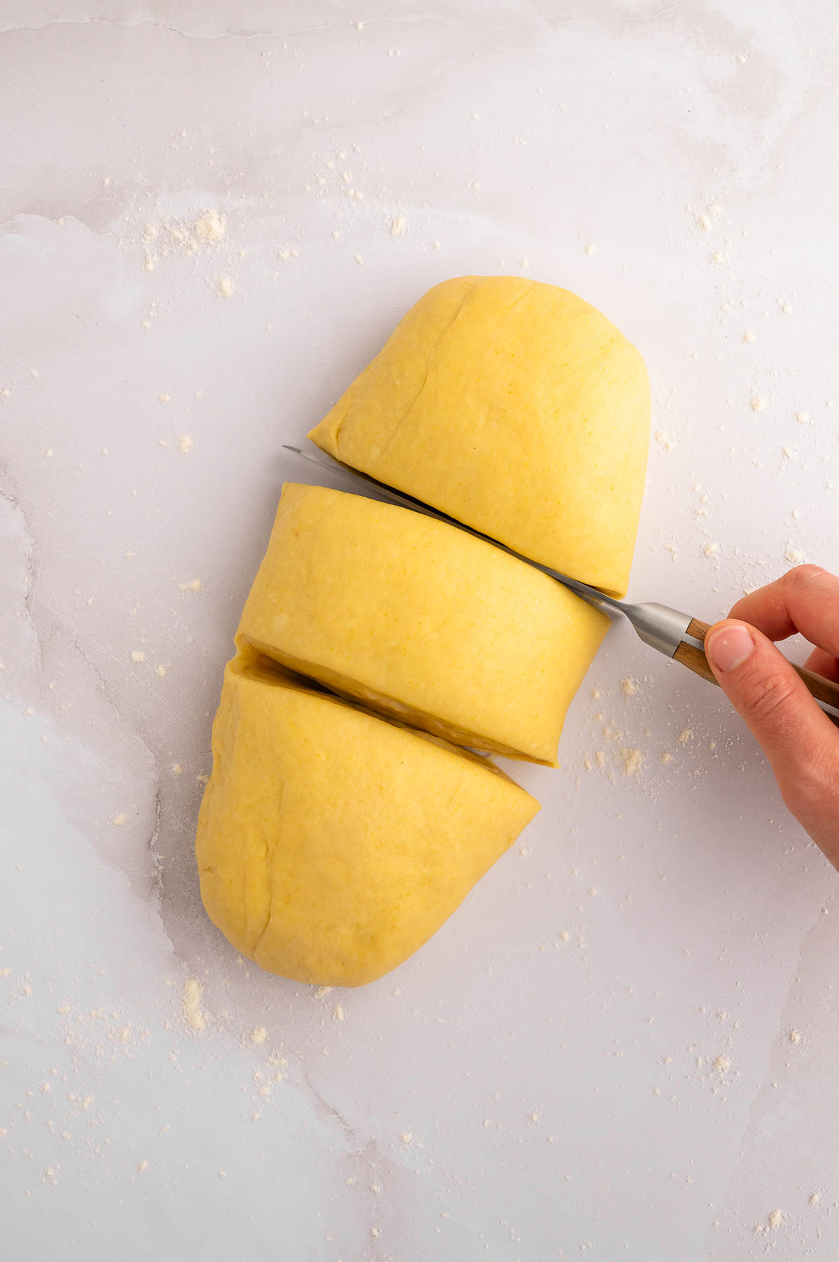 An oval-shaped piece of dough cut into three pieces.