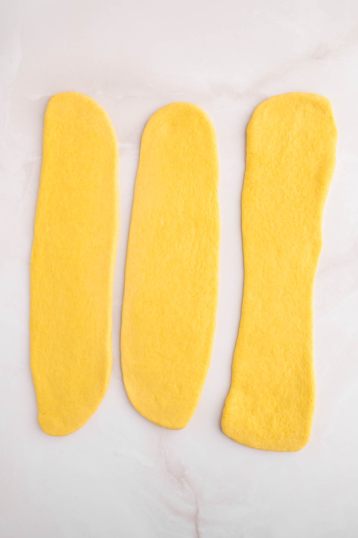 Three long pieces of dough, flattened.