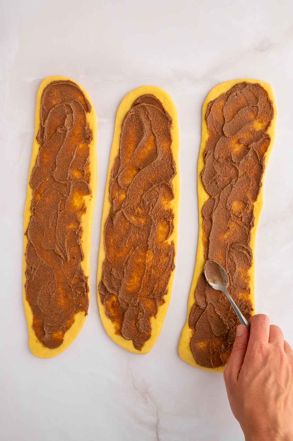 Three portions of cinnamon challah being spread with filling.