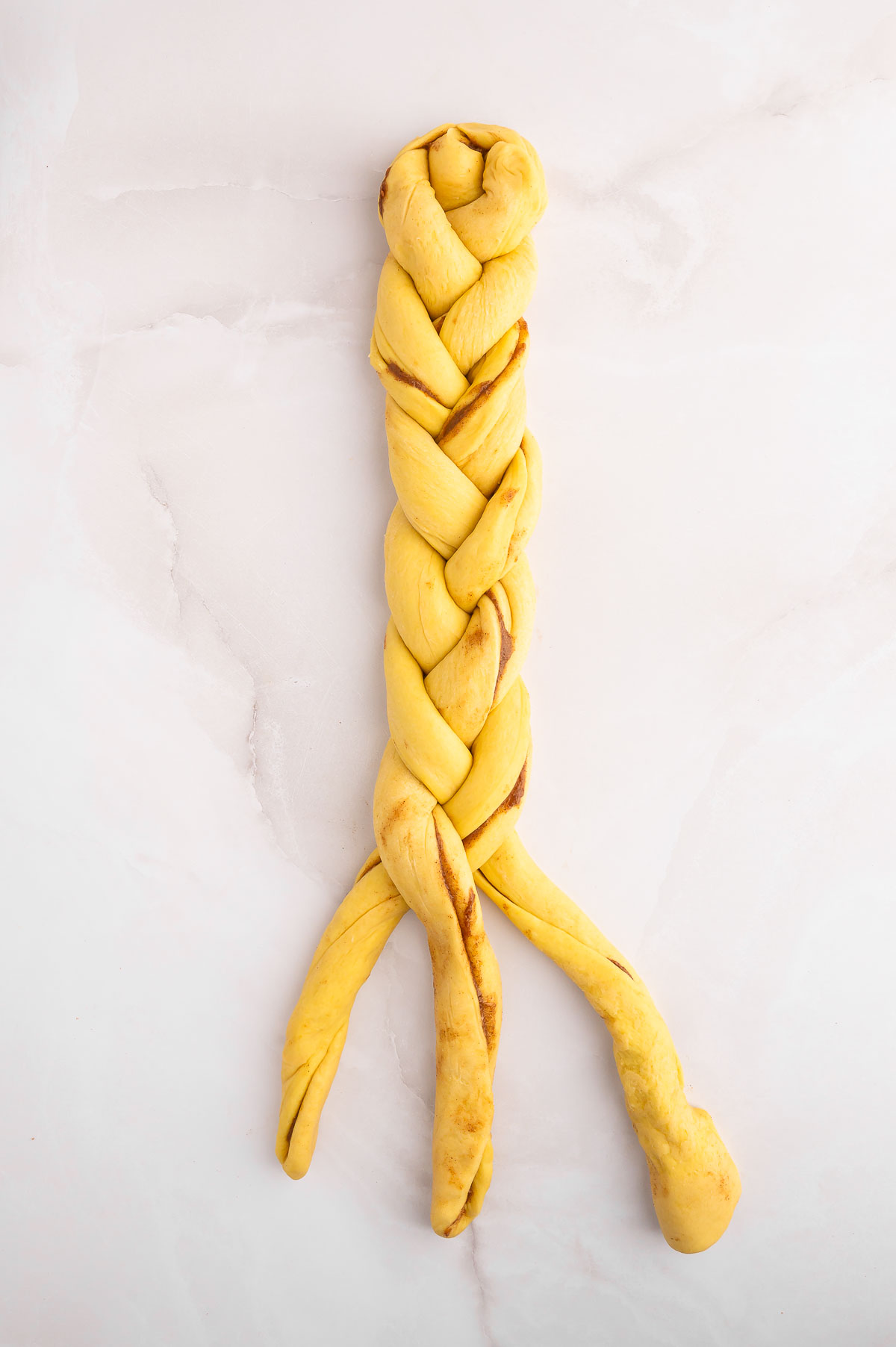 Cinnamon challah dough being braided.