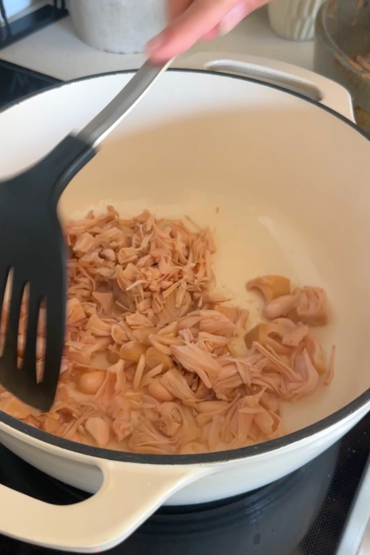 Shredded jackfruit heating up in a large stockpot.