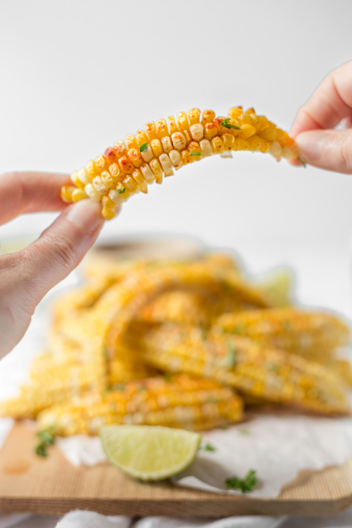 A hand holding up a seasoned corn rib.