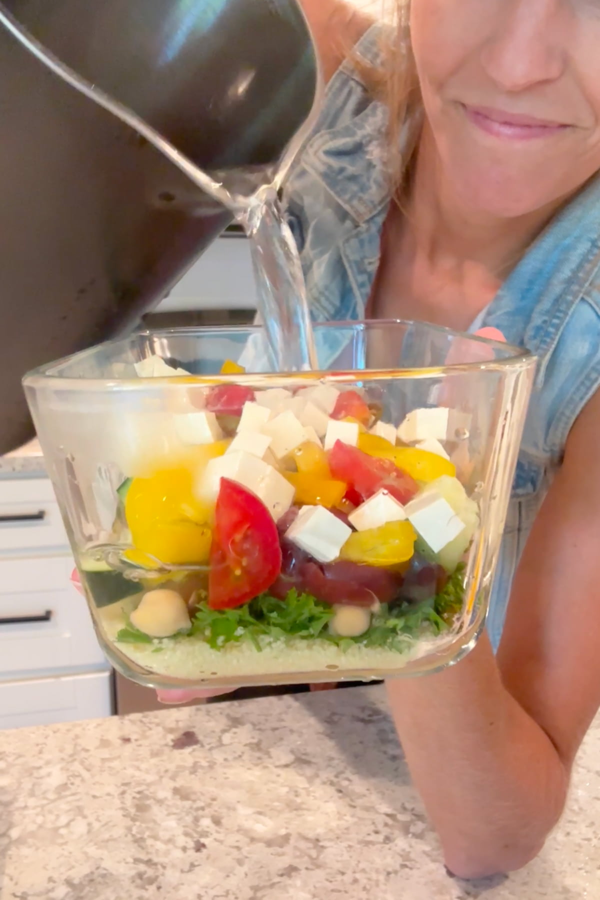 Hot water pouring into the meal prepped couscous bowl.