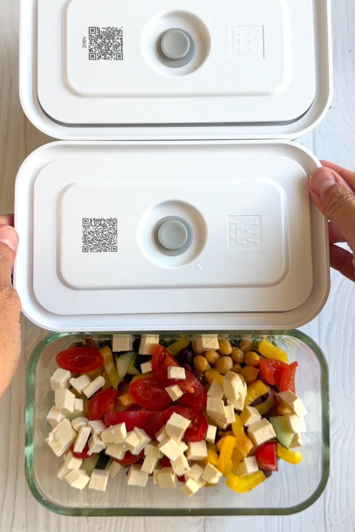 Hands adding lids to the top of the couscous meal prep containers.