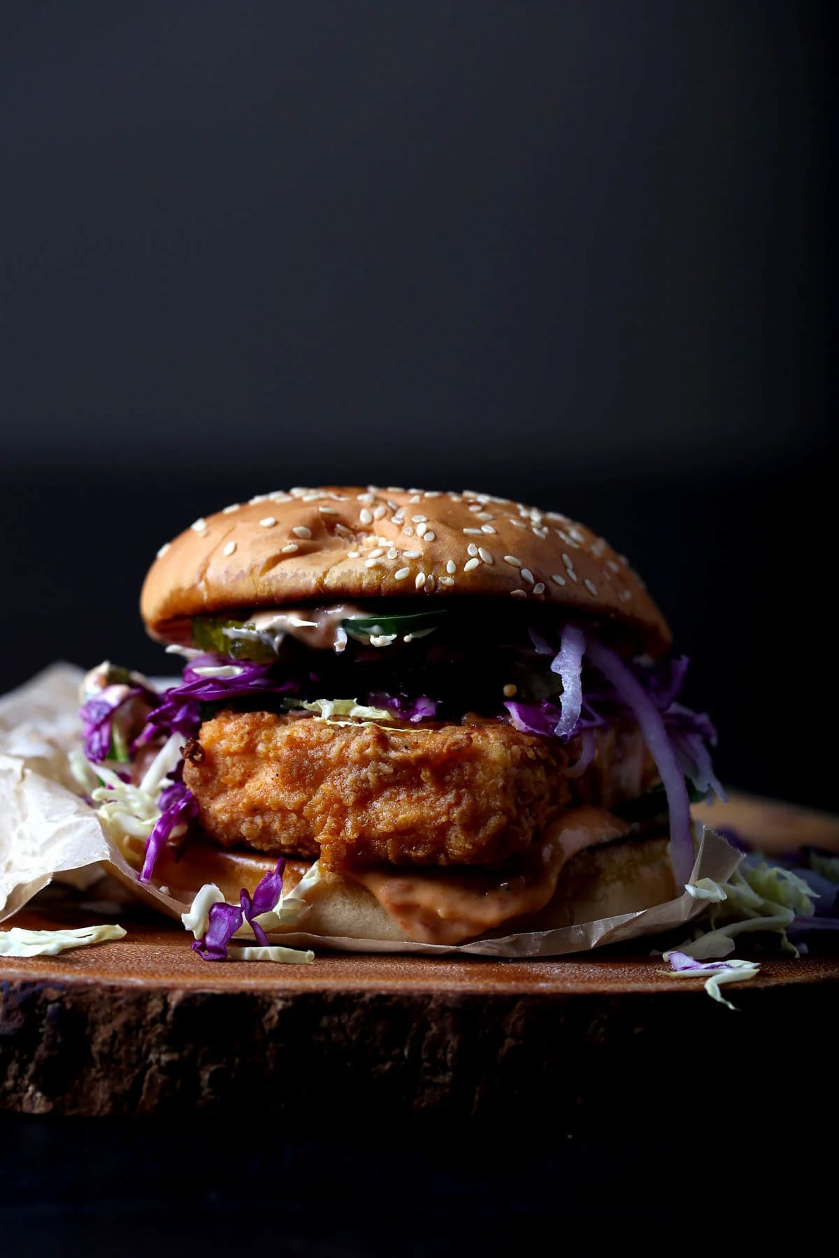 A burger bun filled with crispy fried tofu, cabbage, pickles, and spicy vegan mayo.
