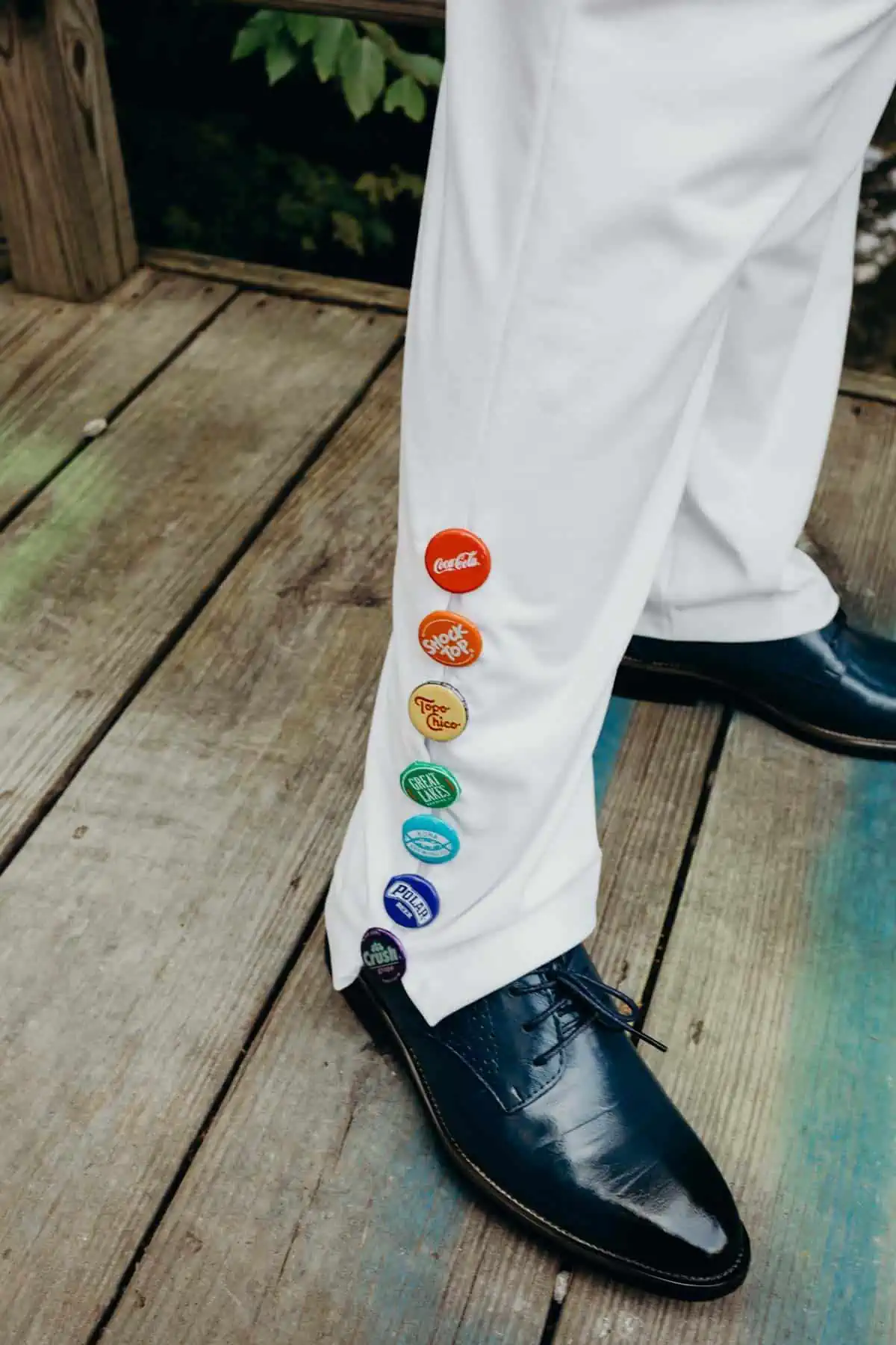 Bottle cap buttons on vegan jumpsuit for creative rainbow wedding outfit.