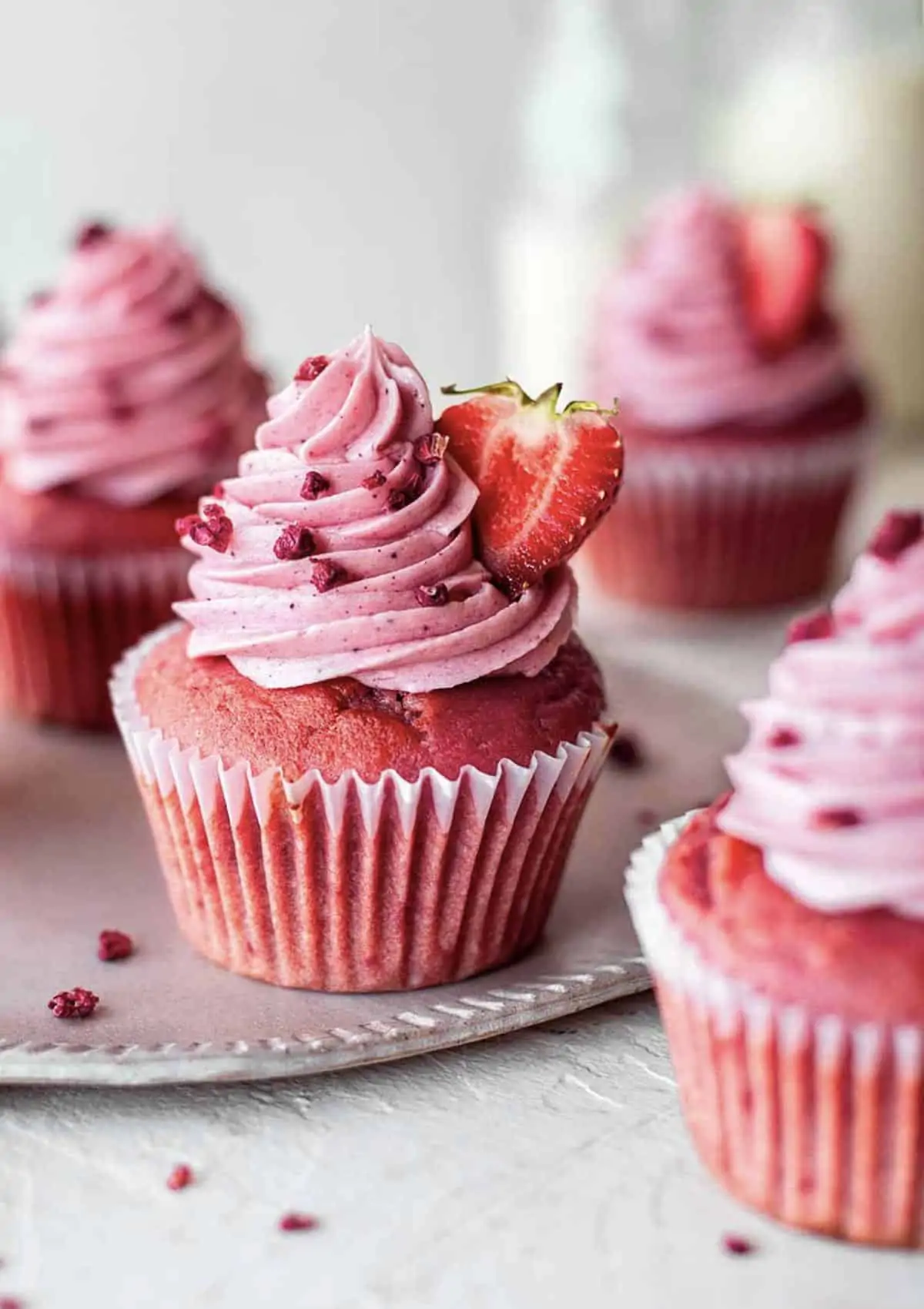 Pink and red cupcakes topped with strawberry frosting.