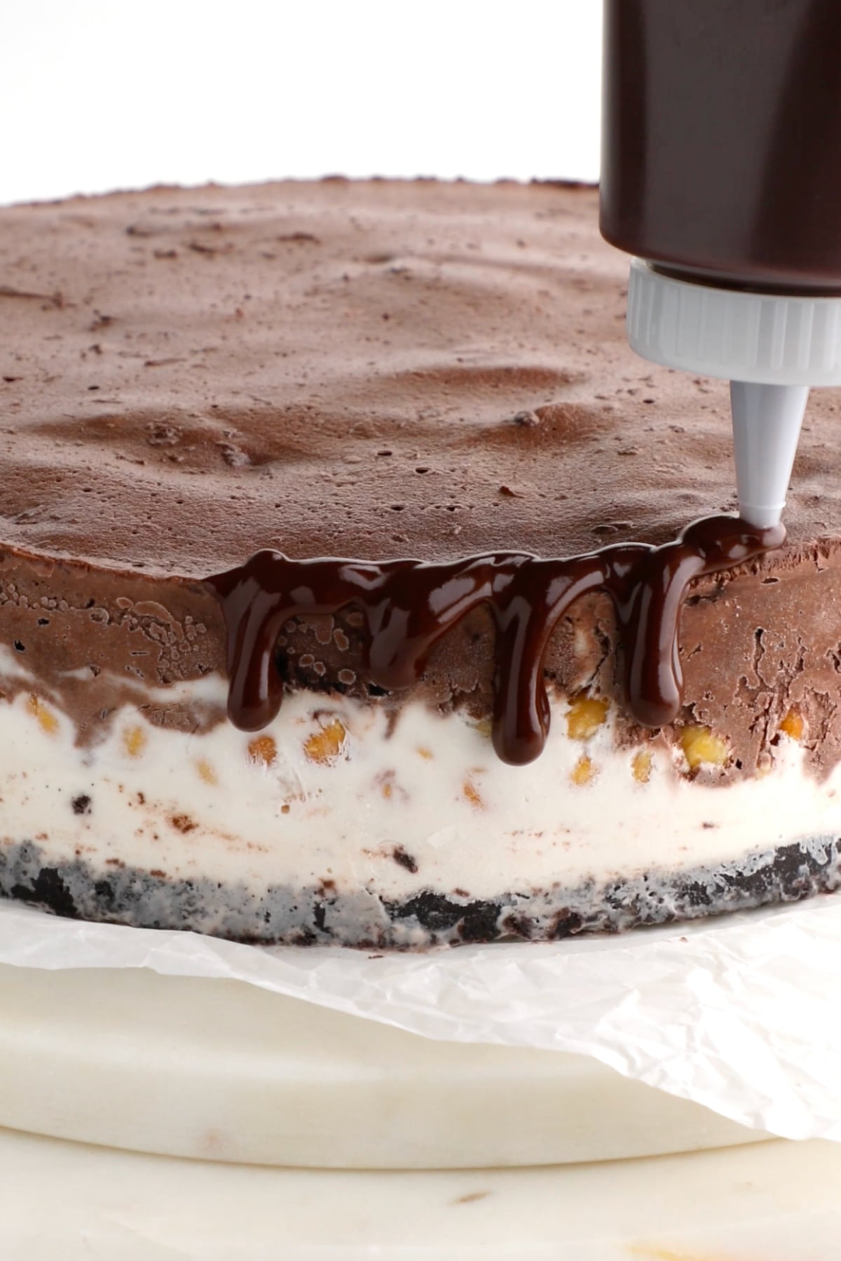 Adding a vegan chocolate ganache drip to the edge of the ice cream cake.