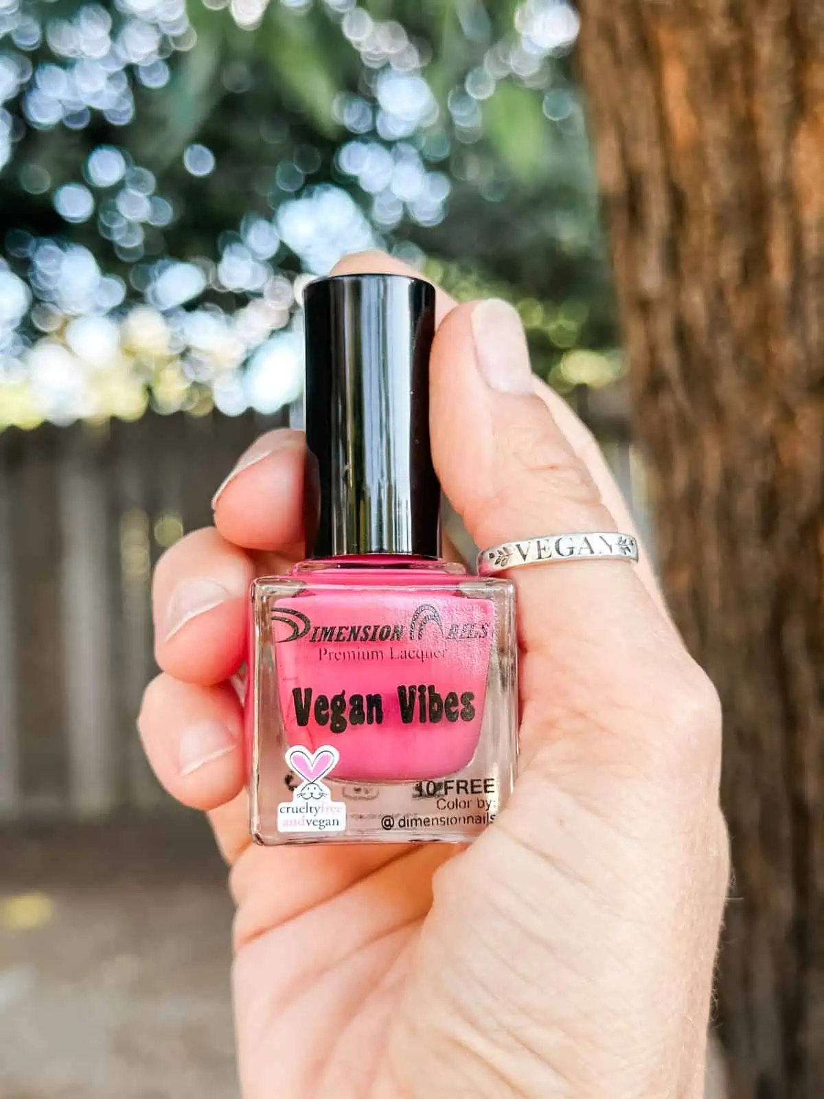 Bottle of pink vegan nail polish from Dimension Nails with the cruelty-free bunny logo.