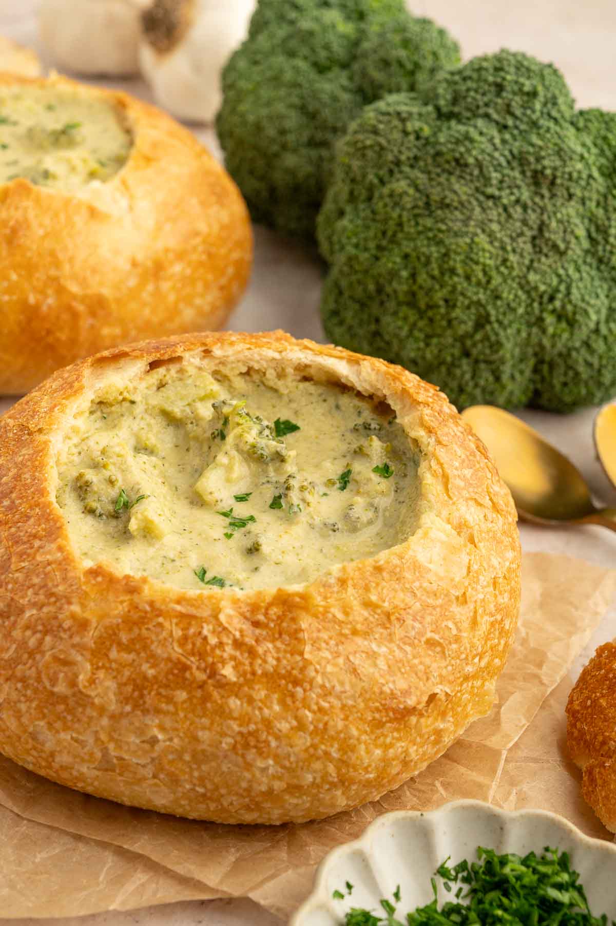 Two bread bowls filled with creamy vegan broccoli cheesy soup.