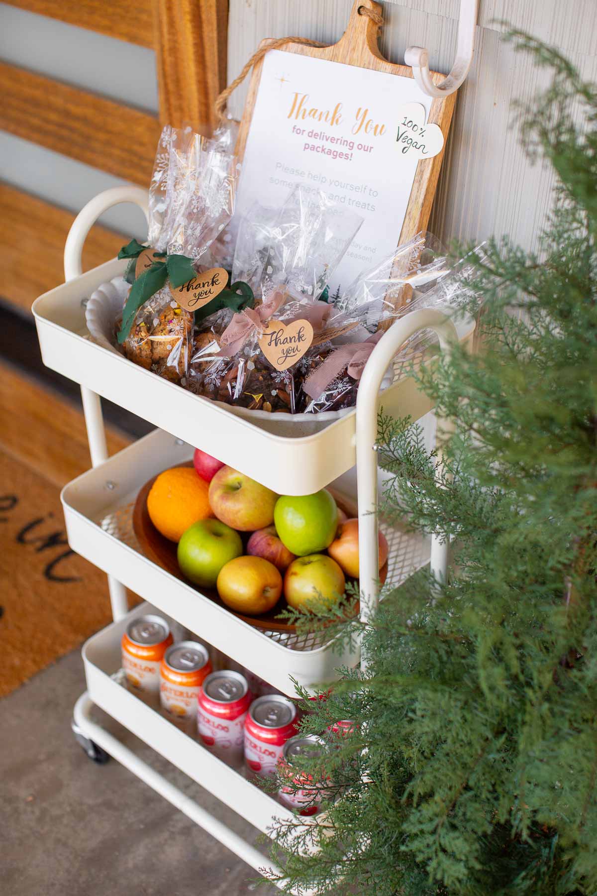 A white snack cart filled with treats and snacks with a sign thanking delivery workers.