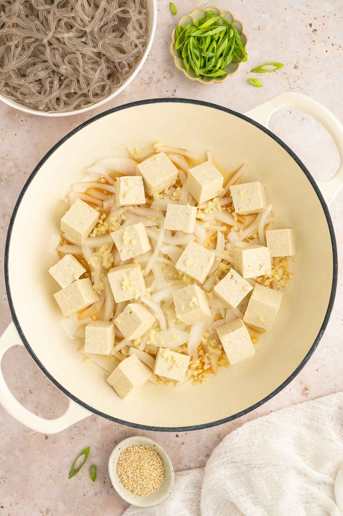 A pan with tofu and sliced onions.