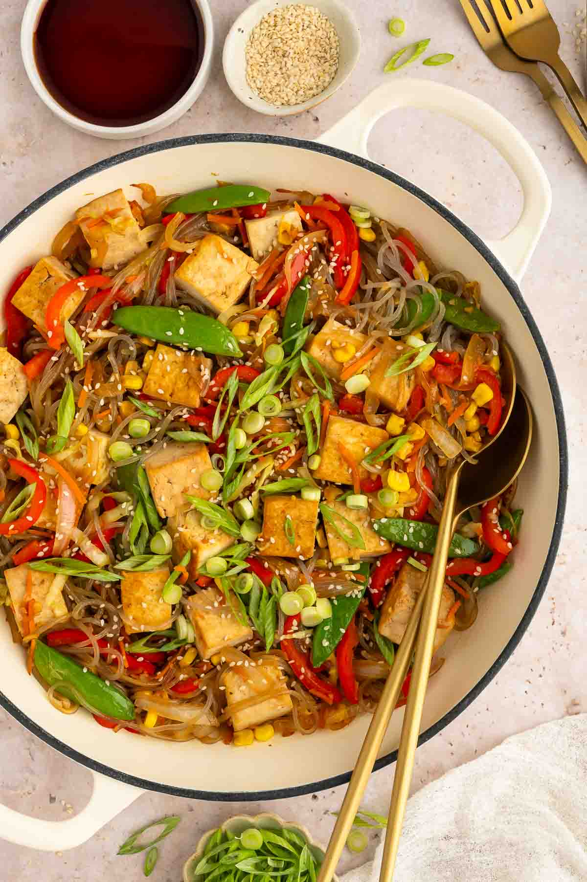 Glass noodles dish with tofu and veggies with utensils.
