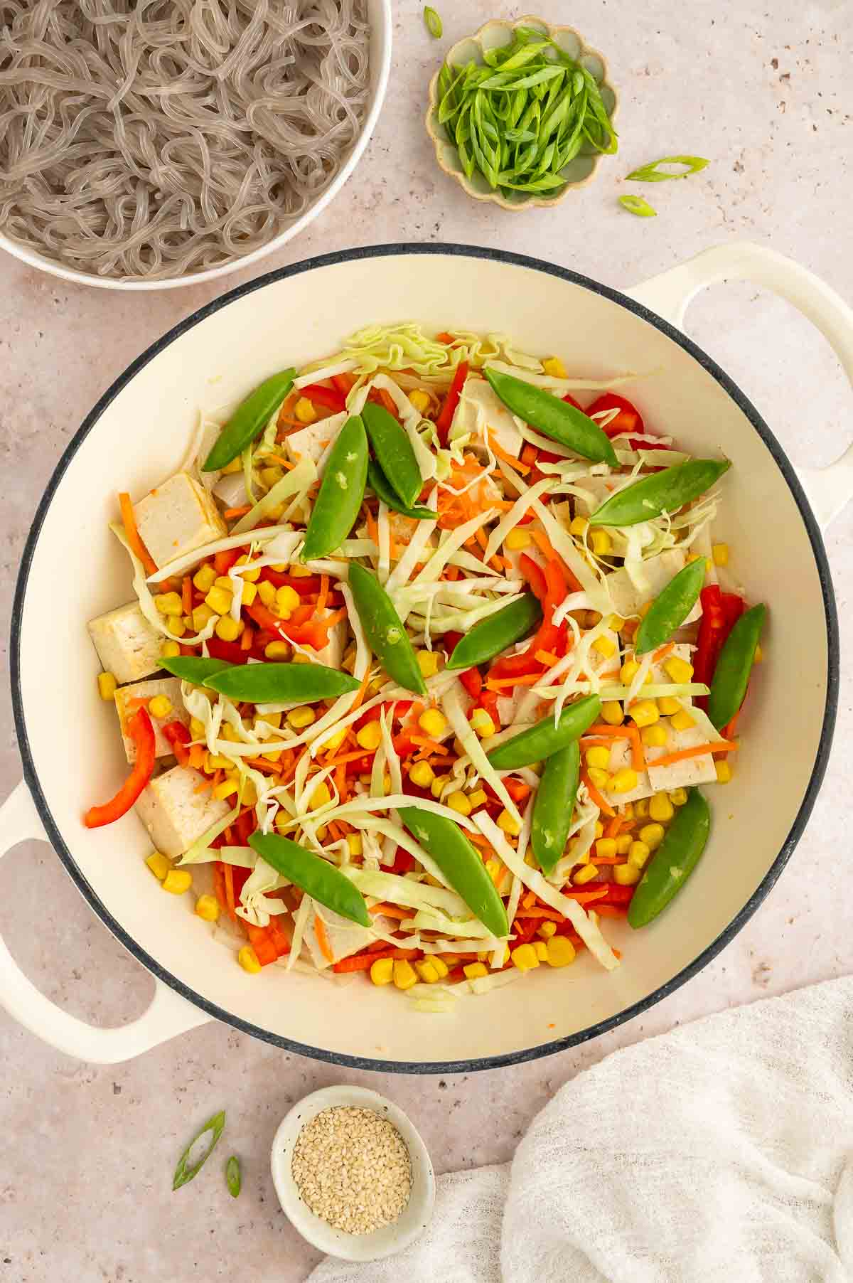 A pan with tofu, snow peas, and other veggies.