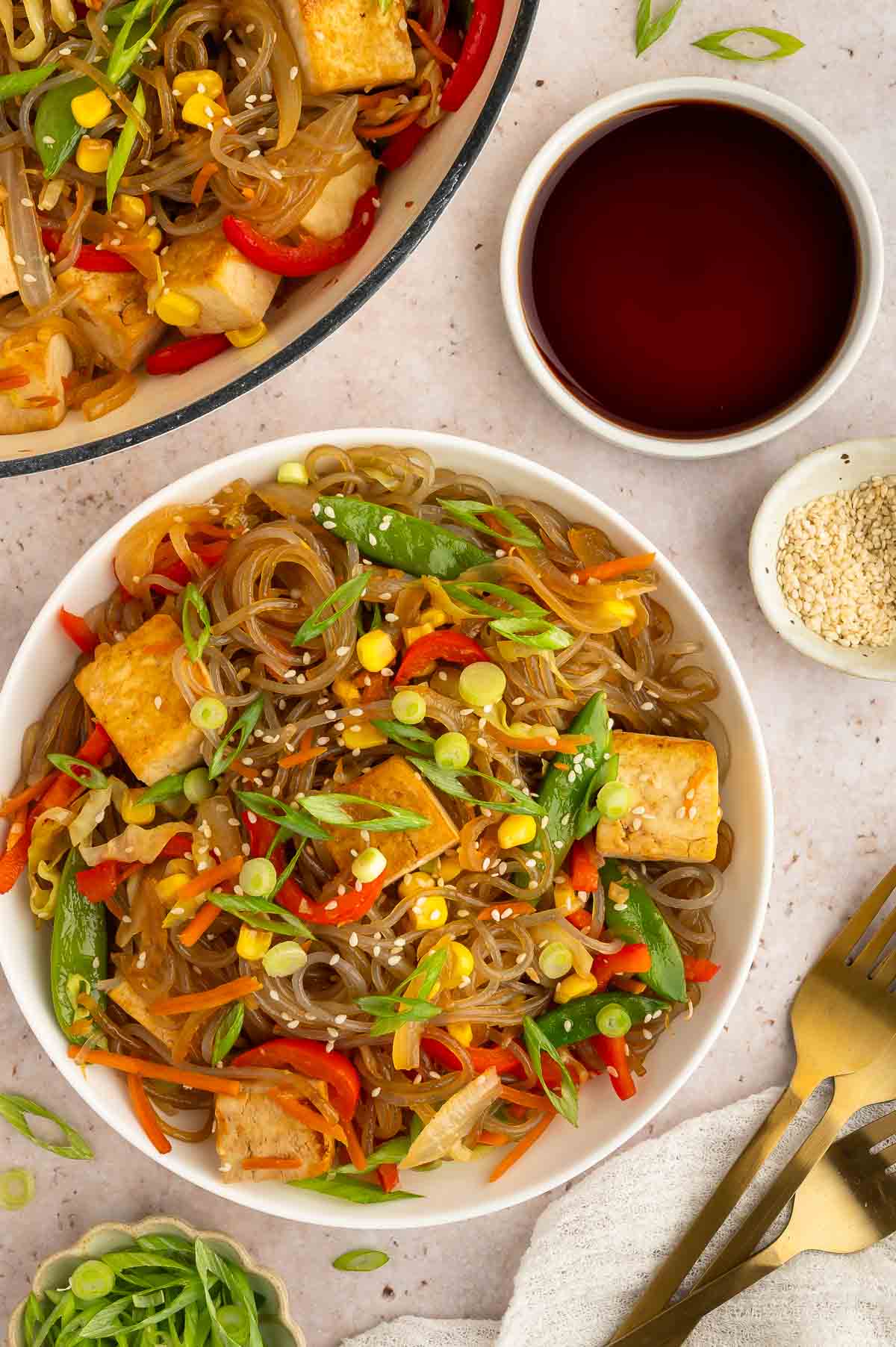 A bowl of glass noodles with tofu and veggies.