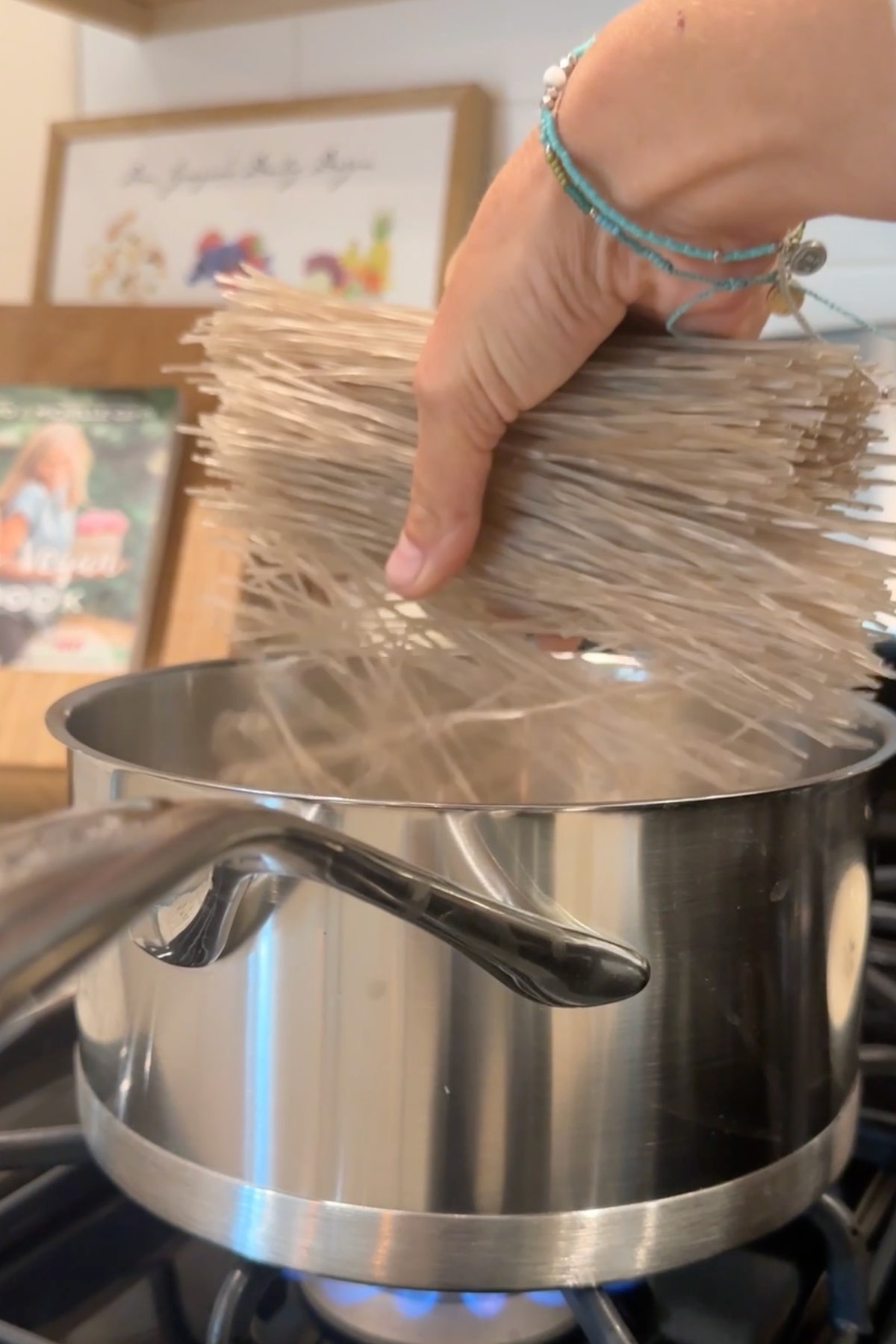 Woman adding glass noodles into a pot of boiling water.