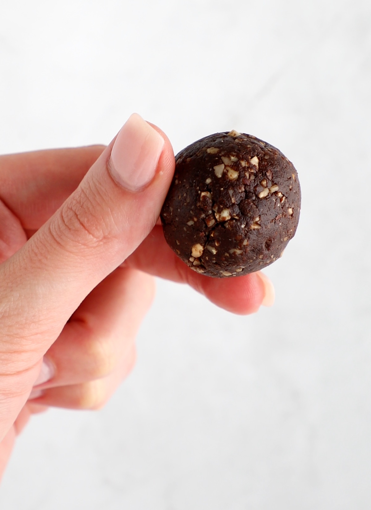A hand holding a vegan protein ball after it's been rolled.
