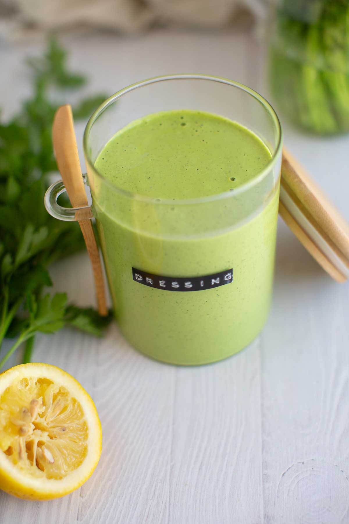 Healthy green goddess dressing in a glass jar with the label "dressing" printed on it.