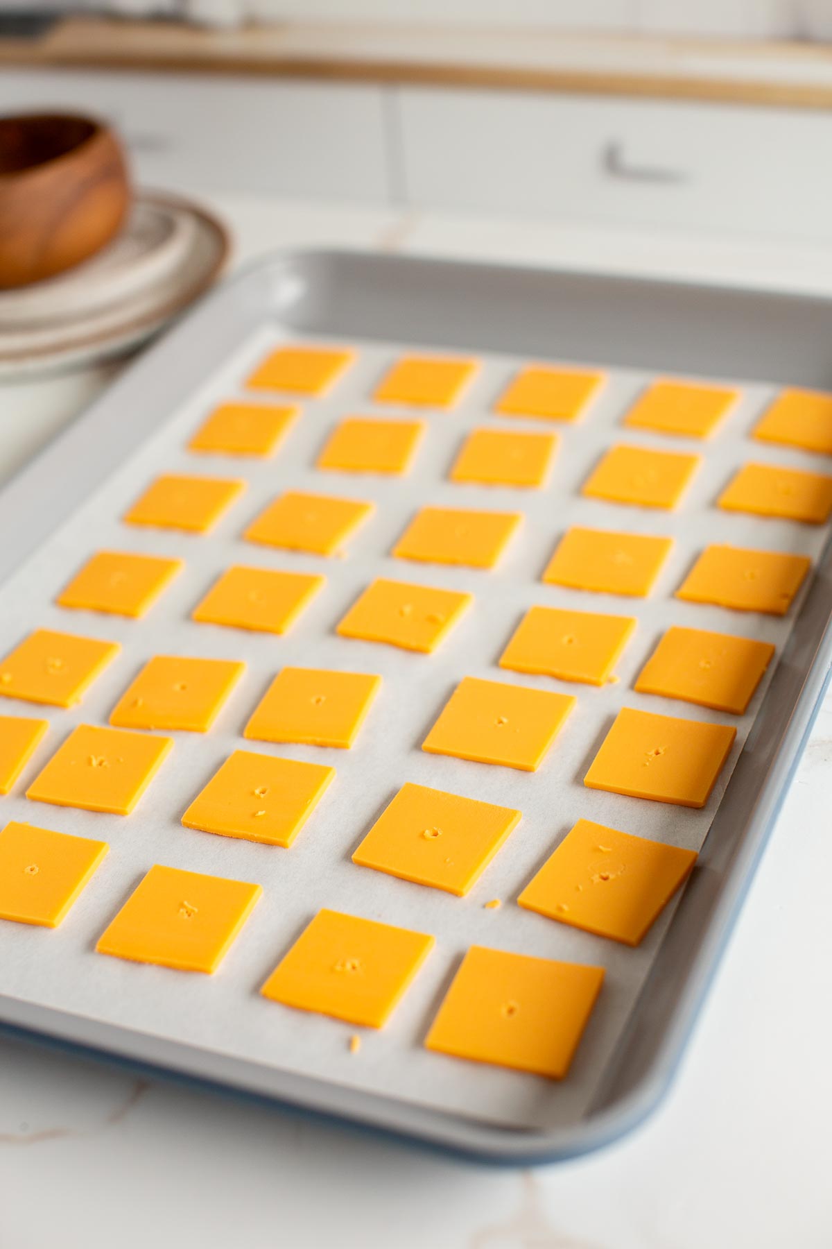 Vegan cheese squares laid out on a baking sheet lined with parchment paper to make Cheez Its.