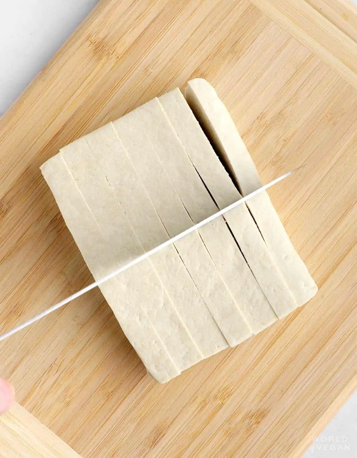 Tofu being cut into cubes for the air fryer.