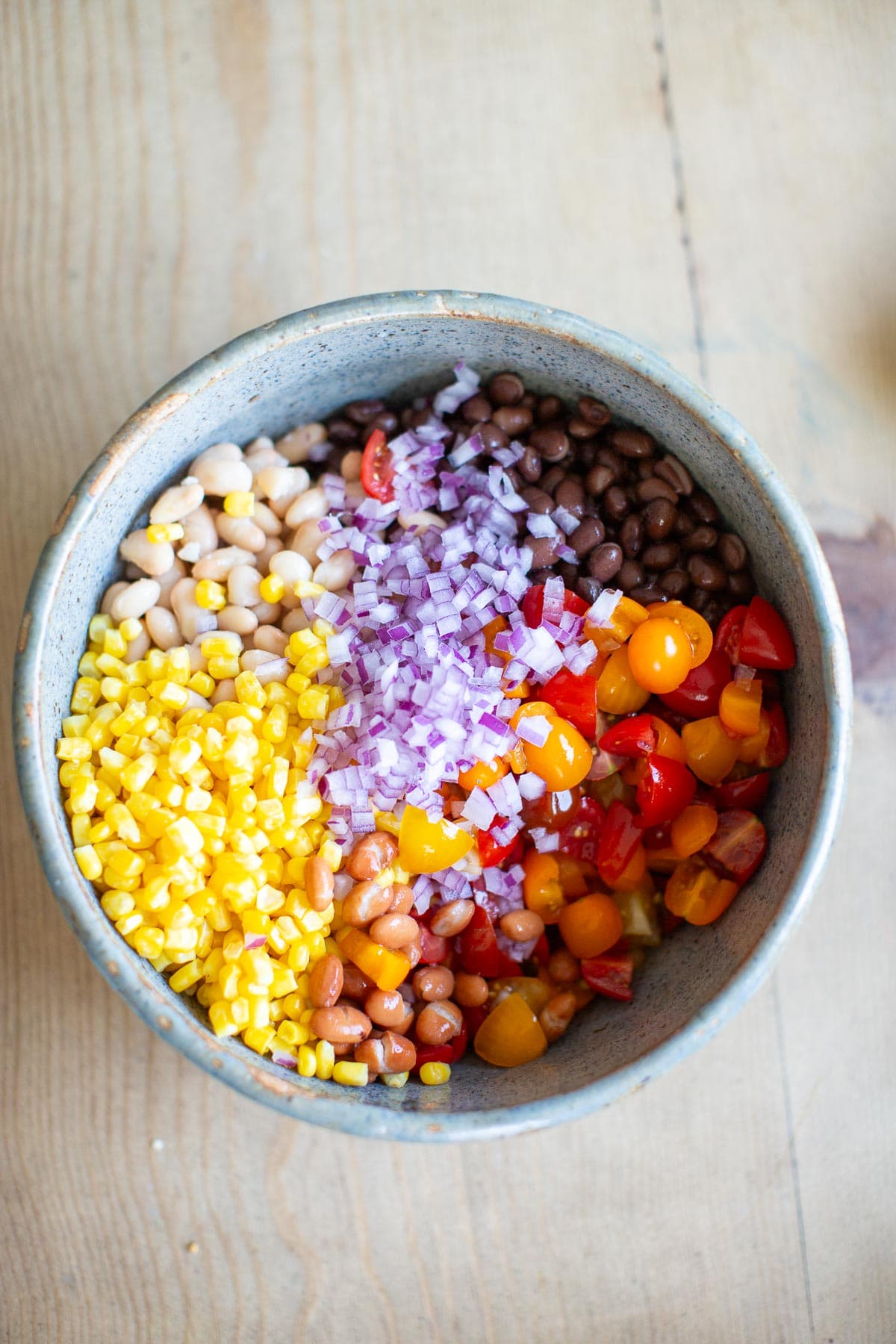 The ingredients for this vegan bean salad added to a large mixing bowl.