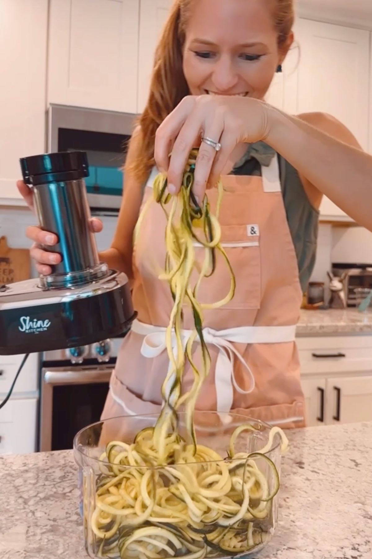 Michelle Cehn spiralizing zucchini into noodle ribbons with an electric spiralizer.