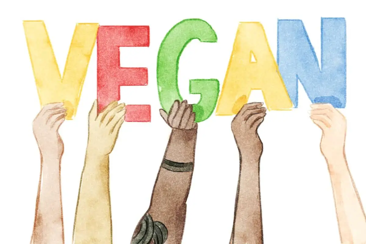 Five arms in different colors and sizes holding up a sign that says VEGAN.