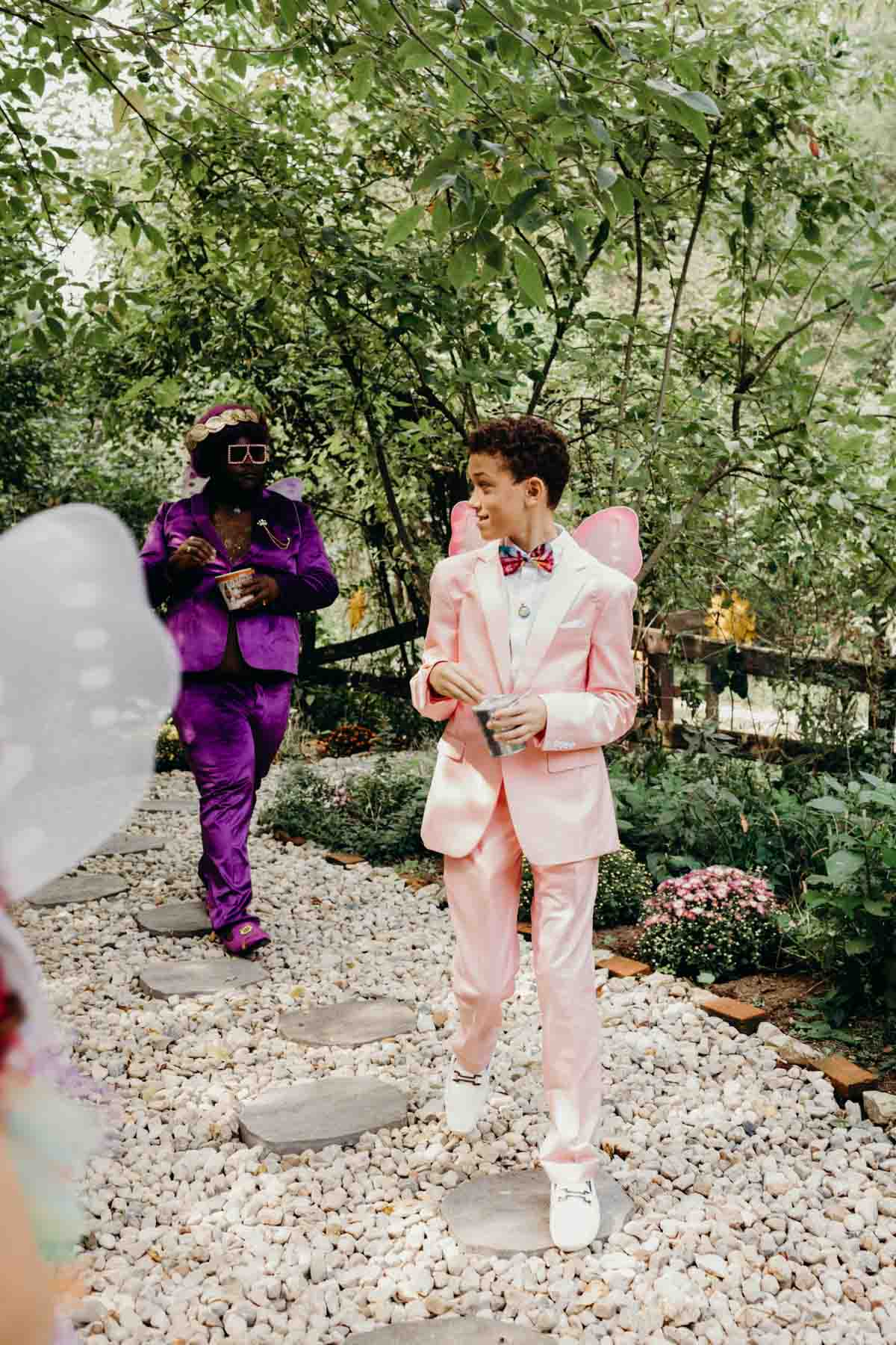 Wedding guests in rainbow fairy-inspired outfits in woodland ceremony.