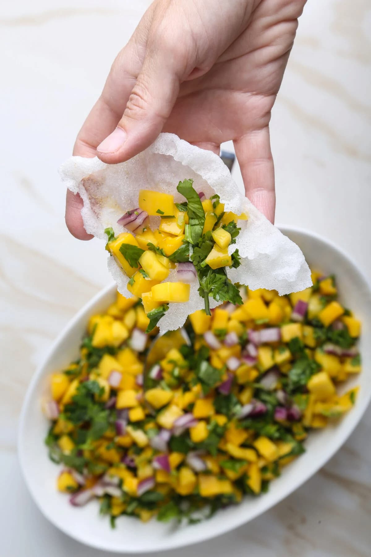 Mango salsa served on a crispy puffed rice paper chip, perfect for a fun vegan BBQ appetizer.