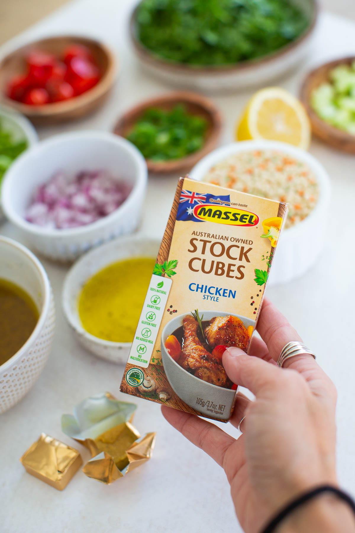A hand holding up a package of Massel chicken style stock cubes.