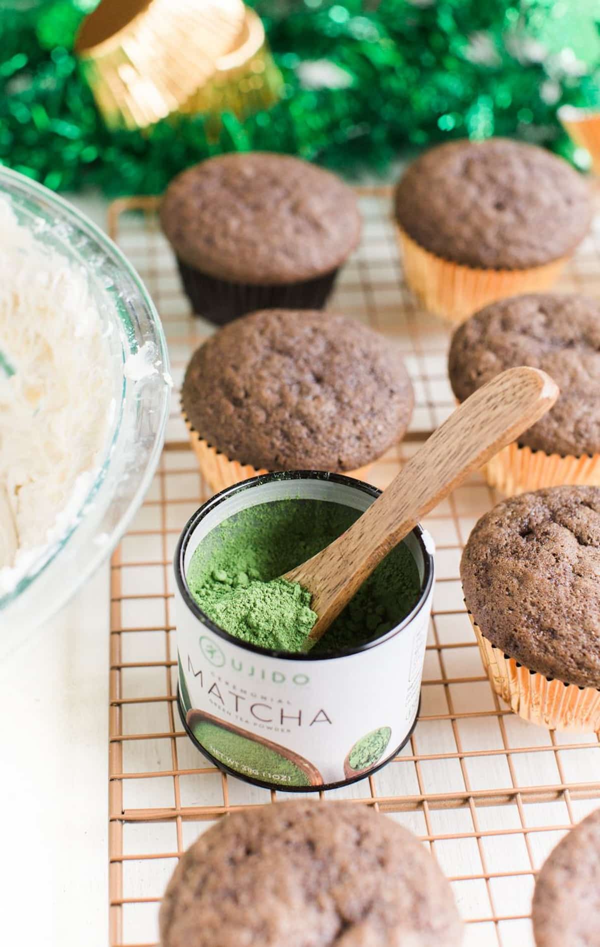 Vegan chocolate cupcakes with a tin of matcha powder next to them.