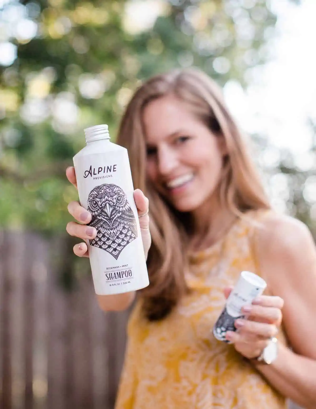 Michelle Cehn holding up cruelty-free and vegan sustainable body wash and shampoo from Alpine Provisions.