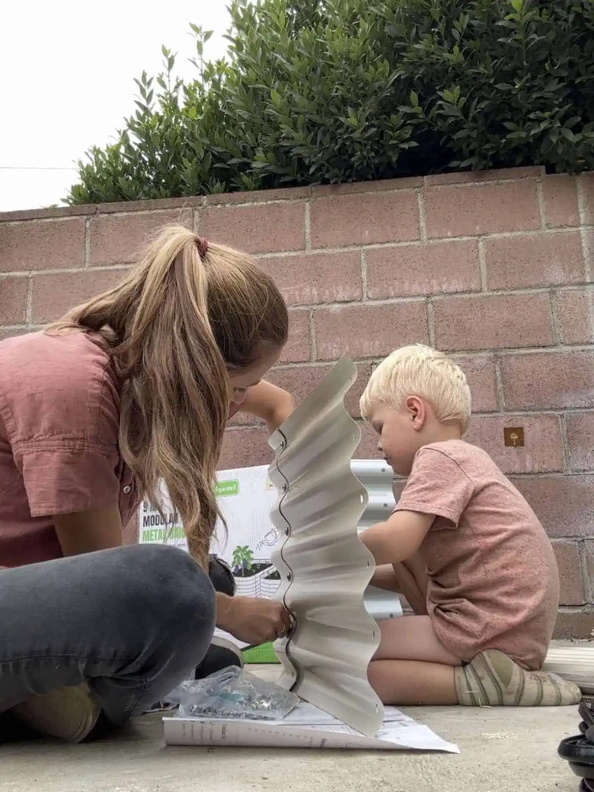 A mother and her young child assembling a modular metal raised garden bed together, preparing for a thriving foodscape.