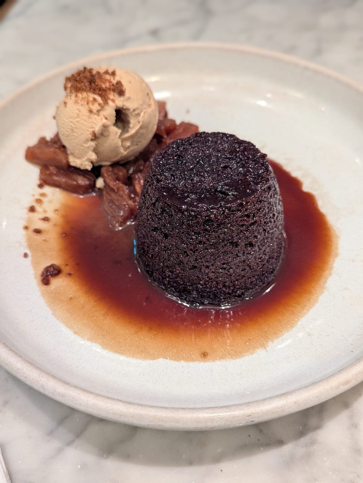 A plate of butter rum sticky toffee and a scoop of vegan salted caramel ice cream.