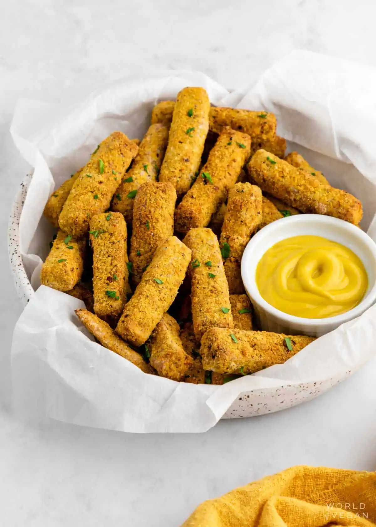 Crispy tofu fries in a bowl served with mustard and garnished with parsley.