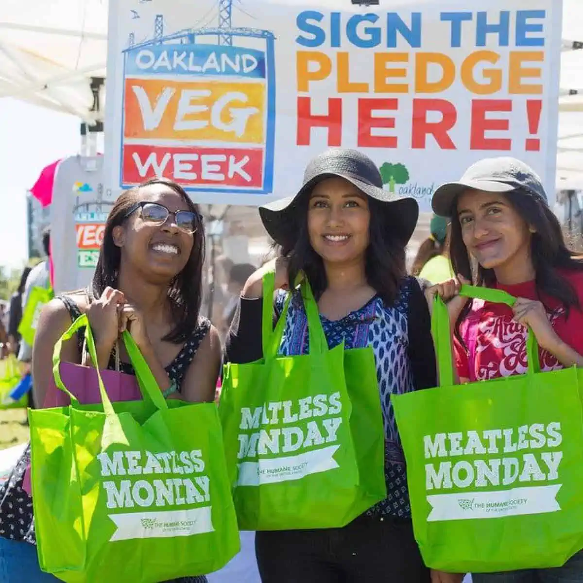 Three girls holding meatless monday bags at oakland vegfest.