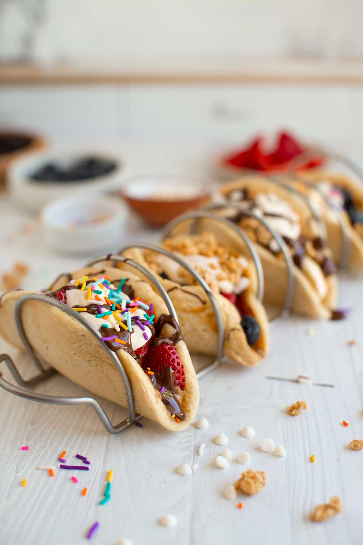 Pancake tacos, in a taco holder, topped with sprinkles.