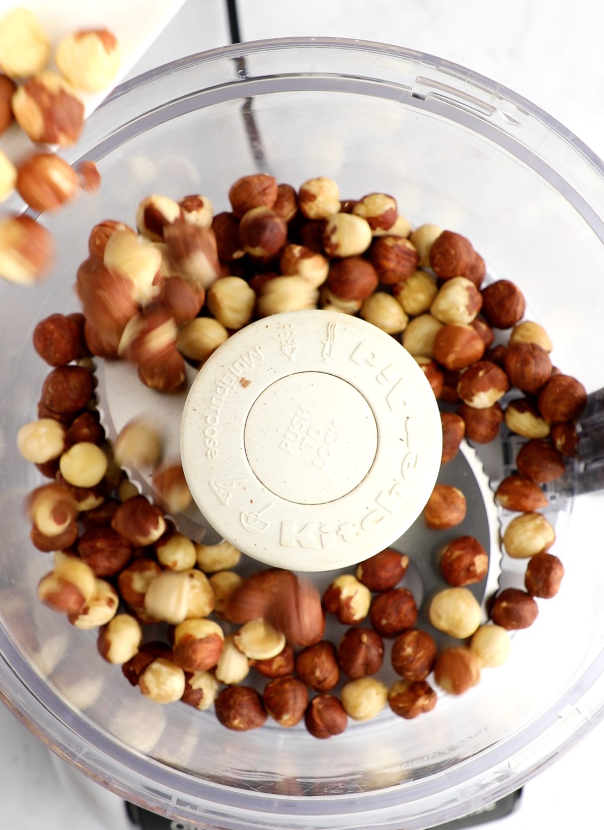 Hazelnuts are added to a food processor.