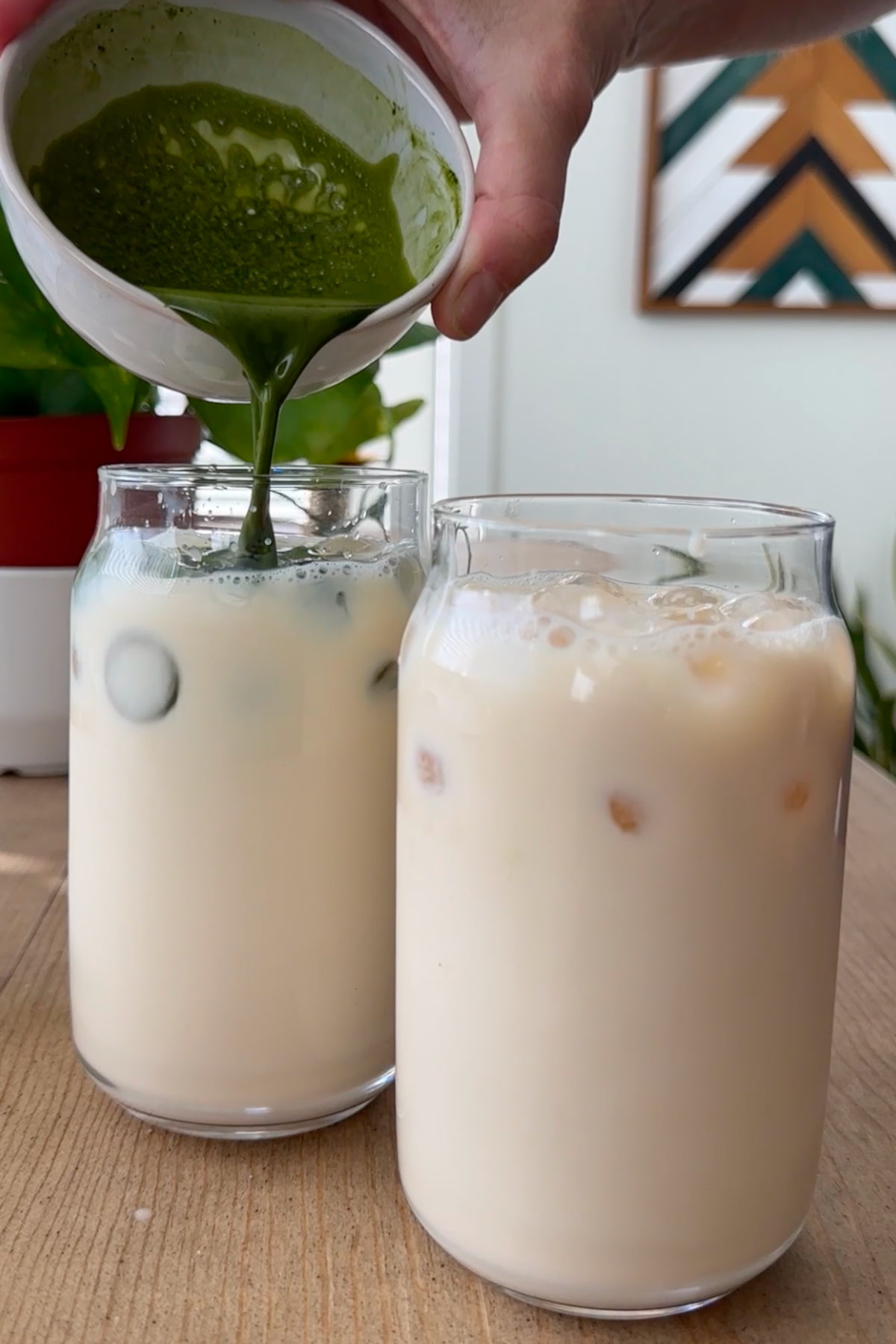 The prepared matcha pouring into the glasses of milk and ice.