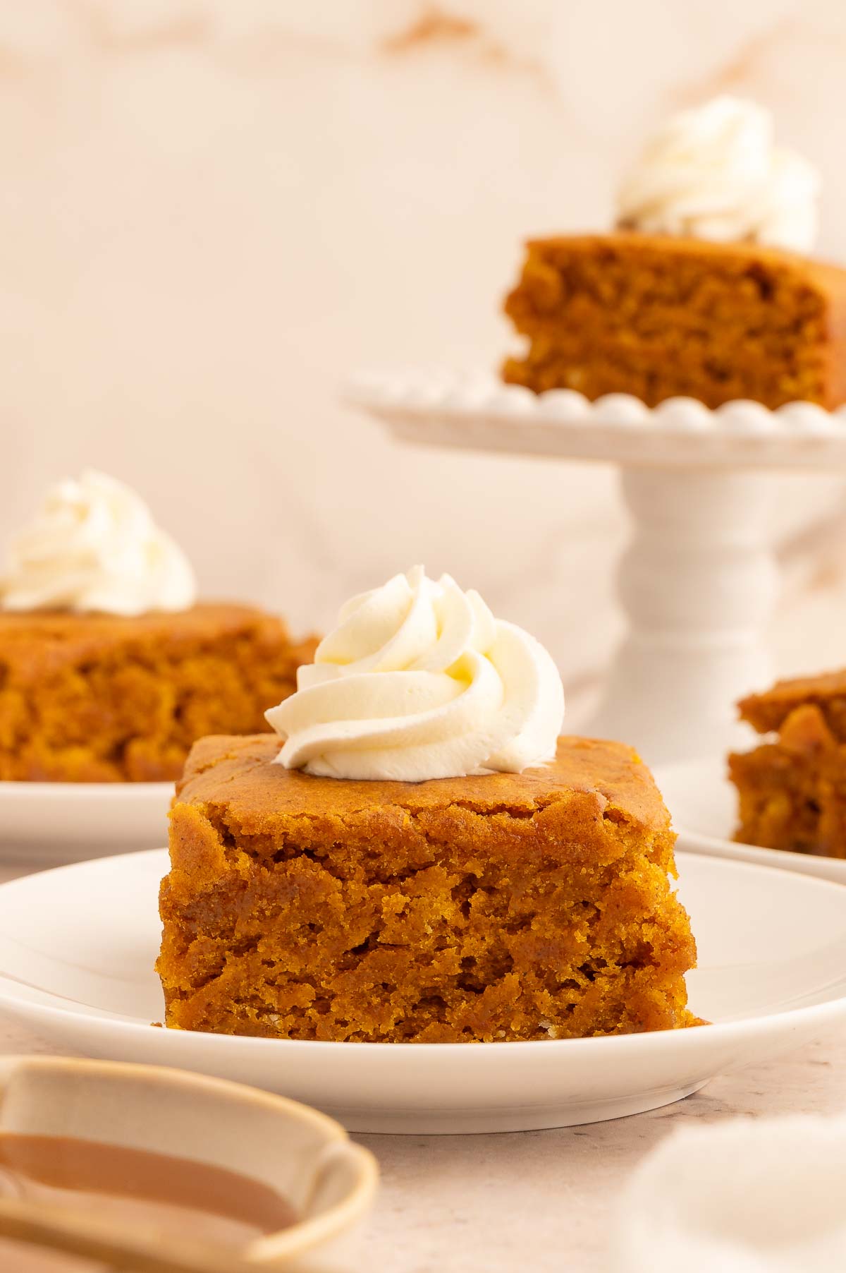 A slice of pumpkin dump cake on a plate, topped with a swirl of dairy-free whipped cream.