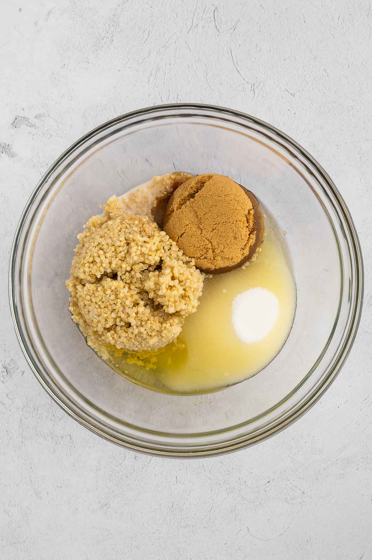 Quinoa, brown sugar, white sugar, and canola oil in a bowl.